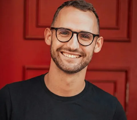 Hugo Bonnetain, fondateur d'Elyria Conseil, souriant devant une porte rouge