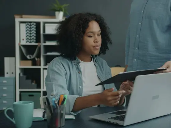 Dirigeante d'une petite entreprise étudiant un document financier avec un collaborateur