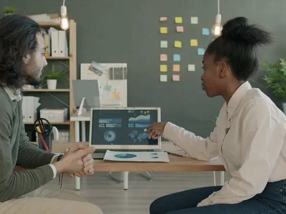 Séance de travail entre un dirigeant et son conseil devant un tableau de bord